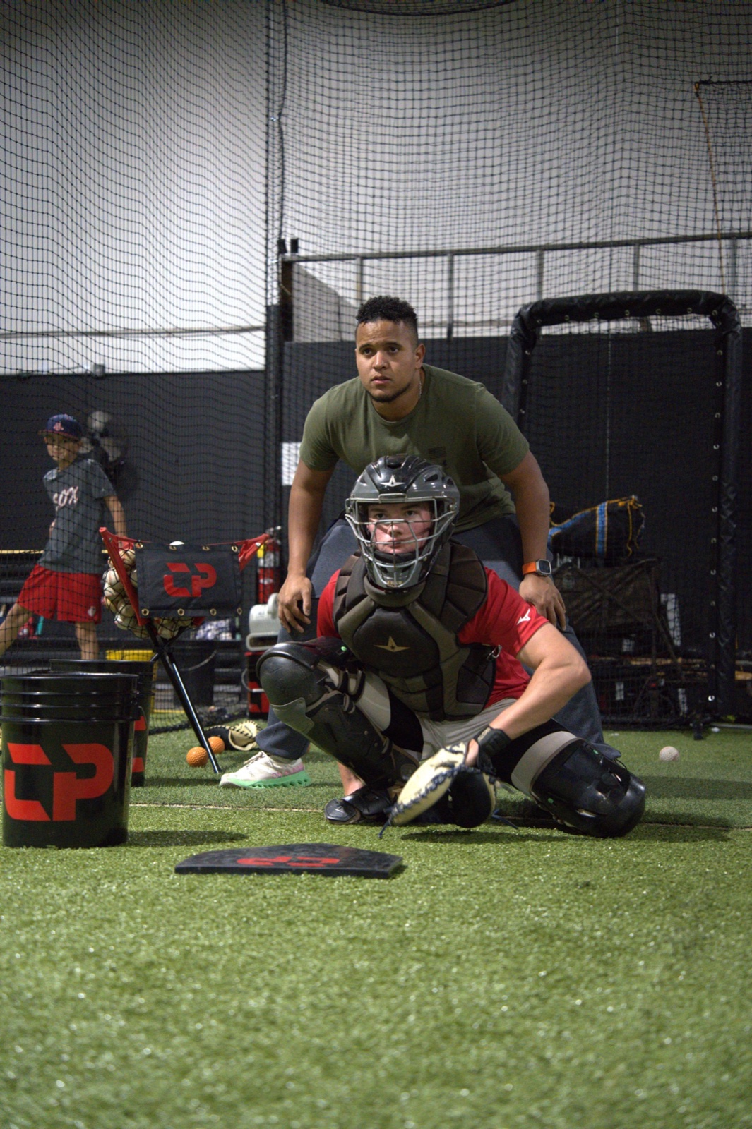 Coach Andrés guiding a catcher through receiving position and setup