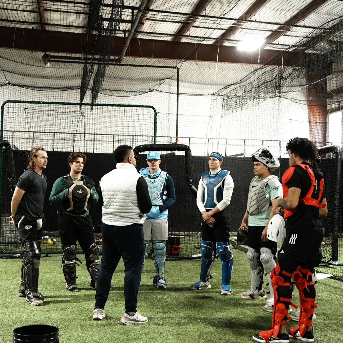 Advanced catchers listening to Coach Andrés during group training