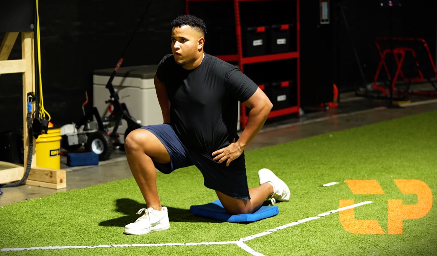 Coach Andrés demonstrating catcher-specific hip mobility on the turf