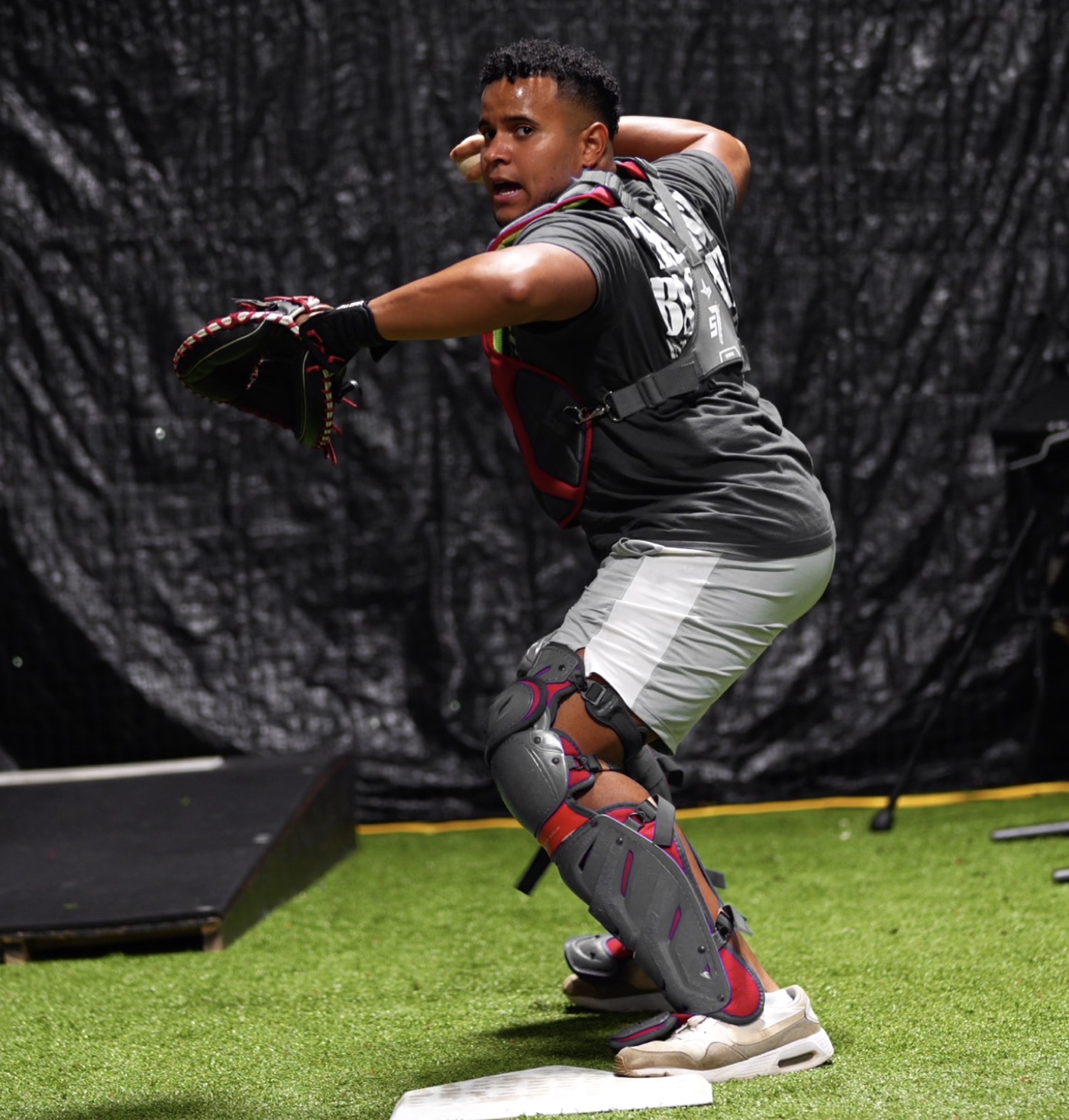 Coach Andrés demonstrating a game-speed catcher throw in full gear