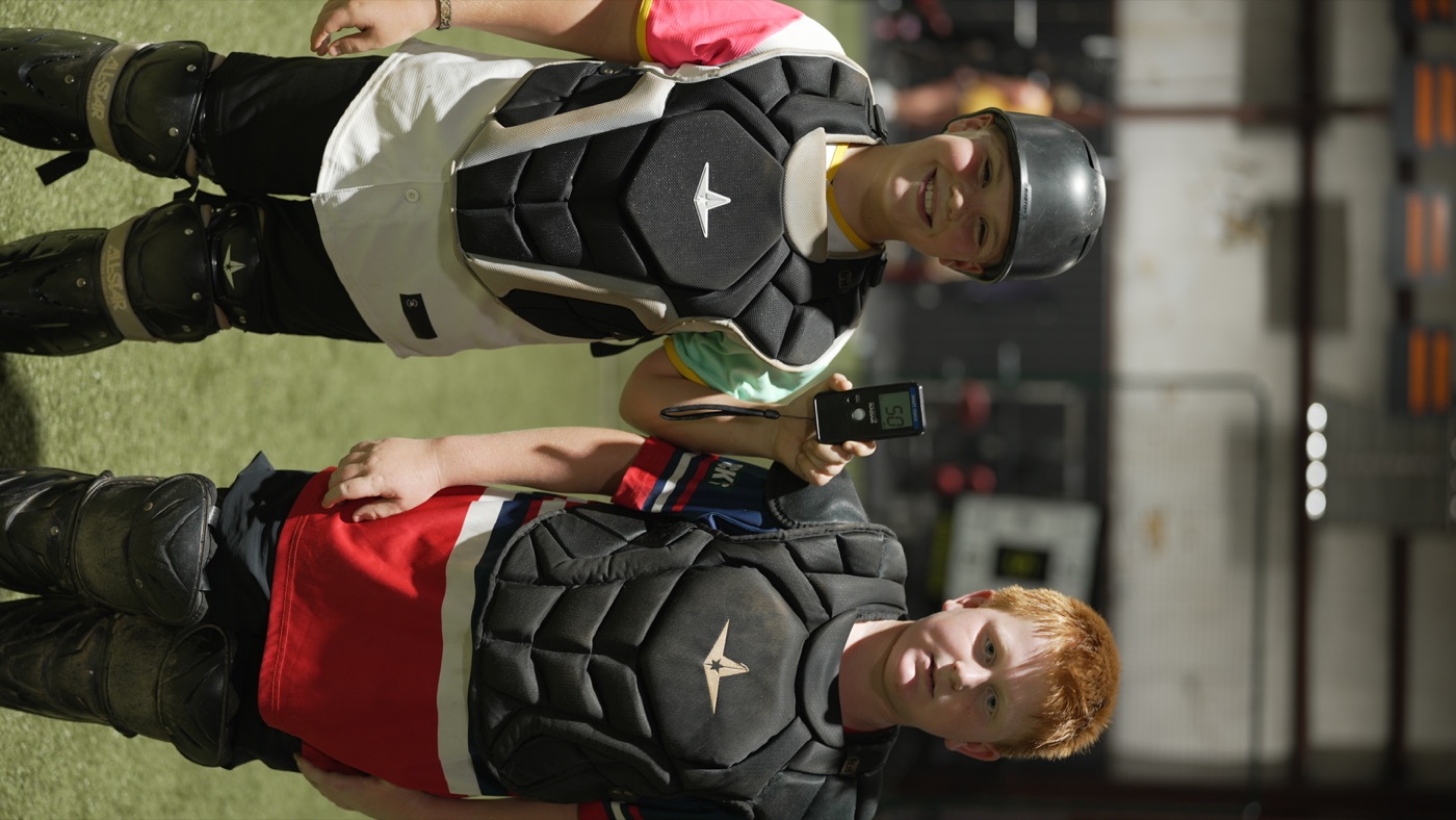 Two catchers holding a radar device after throwing training